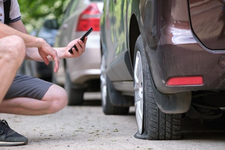 Driver calling road service for assistance having vehicle trouble with a flat tire