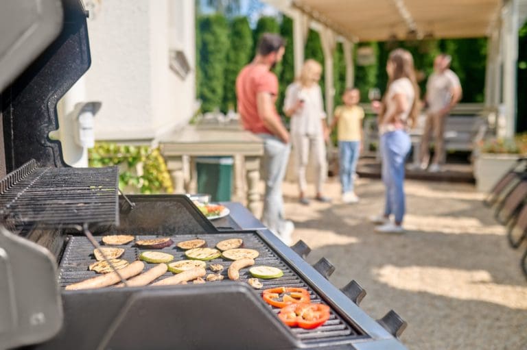 Family gathering in backyard preparing fresh barbequed food