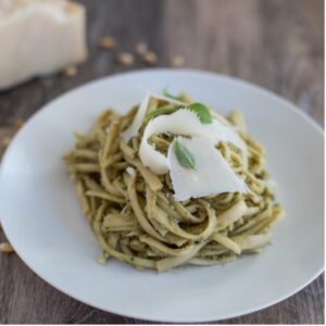Artichoke Pesto Linguine with Chicken on a white plate next to fresh parmesan 