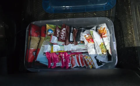 Plastic bin of assorted packaged snacks in vehicle