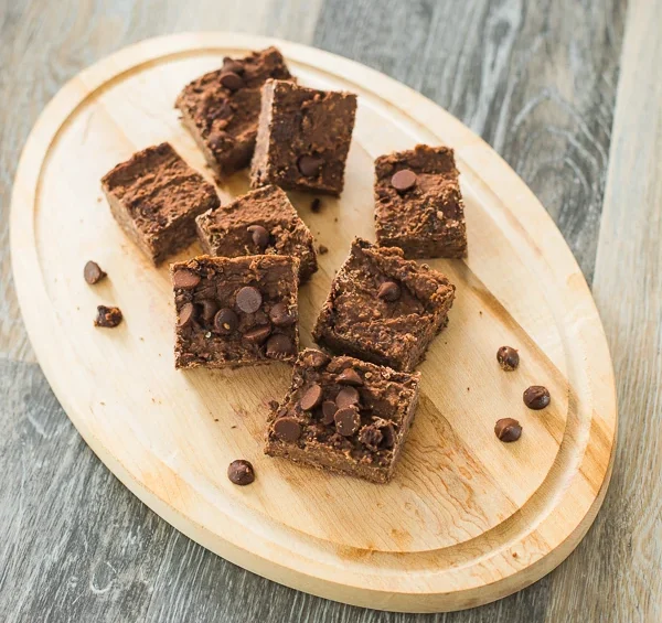 Chocolate brownie squares with chocolate chips served on a wooden board.
