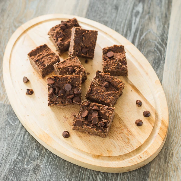Chocolate brownie squares with chocolate chips served on a wooden board.