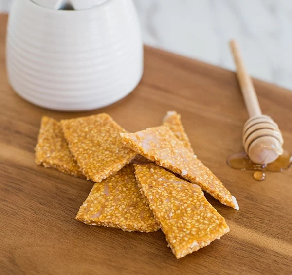 Sesame seed crisps with honey on a wooden board.