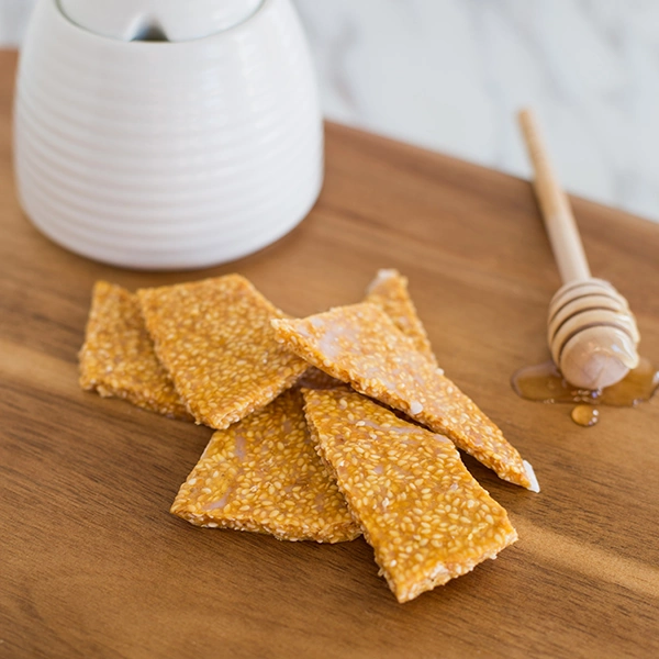 Sesame seed crisps with honey on a wooden board.