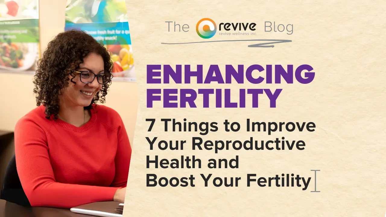 A smiling woman with curly hair and glasses, wearing a red sweater, works on a laptop. Next to her, the text reads: “Enhancing Fertility: 7 Things to Improve Your Reproductive Health and Boost Your Fertility.” This is part of the Revive Wellness Blog.