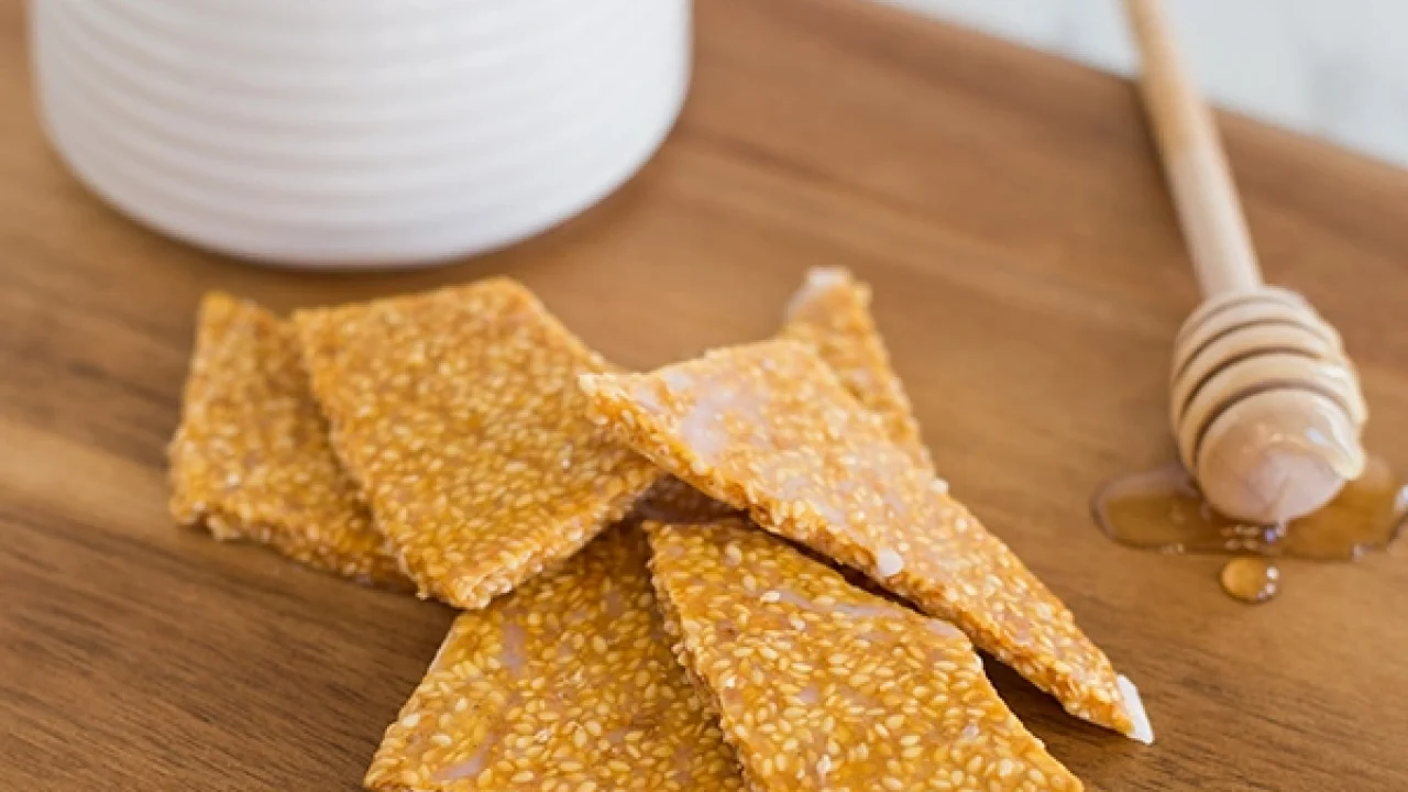 Sesame seed crisps with honey on a wooden board.
