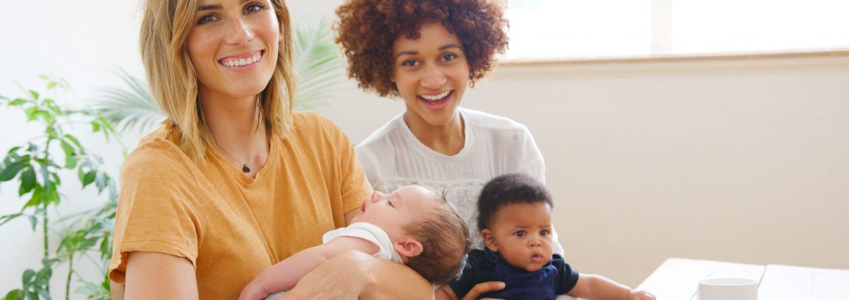 Portrait Of Two Mothers With Babies Meeting And Talking Around Table On Play Date At Home